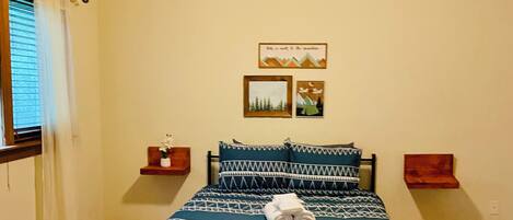 A bedroom with a bed, a ceiling fan, and two wall-mounted side tables.