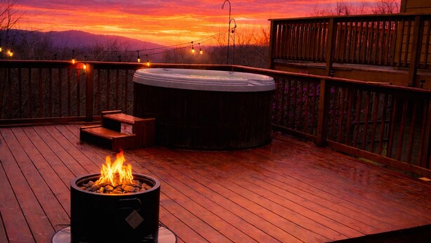 A hot tub on a wooden deck with a fire feature, surrounded by a wooden fence and string lights. - Timber frame chalet with incredible views minutes from Shenandoah National Park. (Linden)