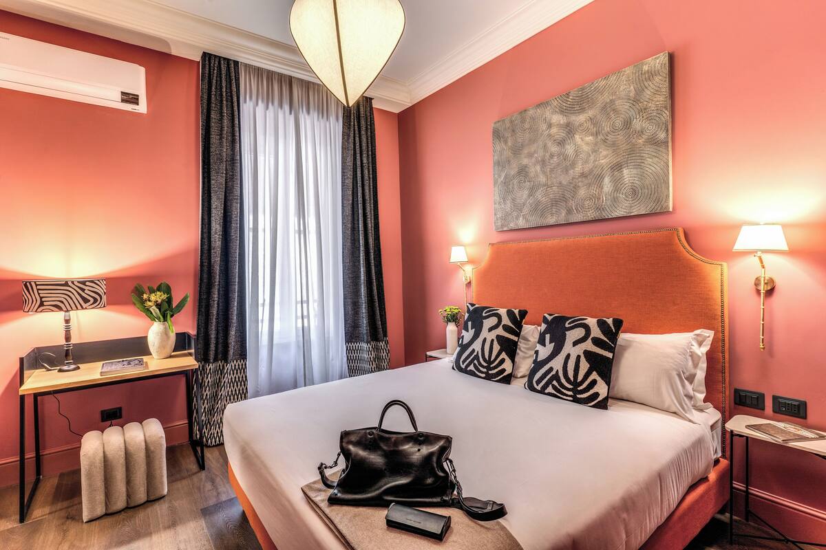A hotel room with a bed, desk, and a large window with curtains.