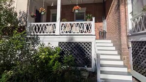 A two-story house with a covered porch, white railings, and a brick exterior. - Historic Charm Meets Modern Comfort in Downtown Burlington (Burlington)