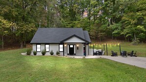 A small, single-story building with a dark roof and white exterior walls, surrounded by a grassy area and trees. - The Cumberland Collective~The Hideaway~<6mi to lake/golf. Great for families! (Burkesville)