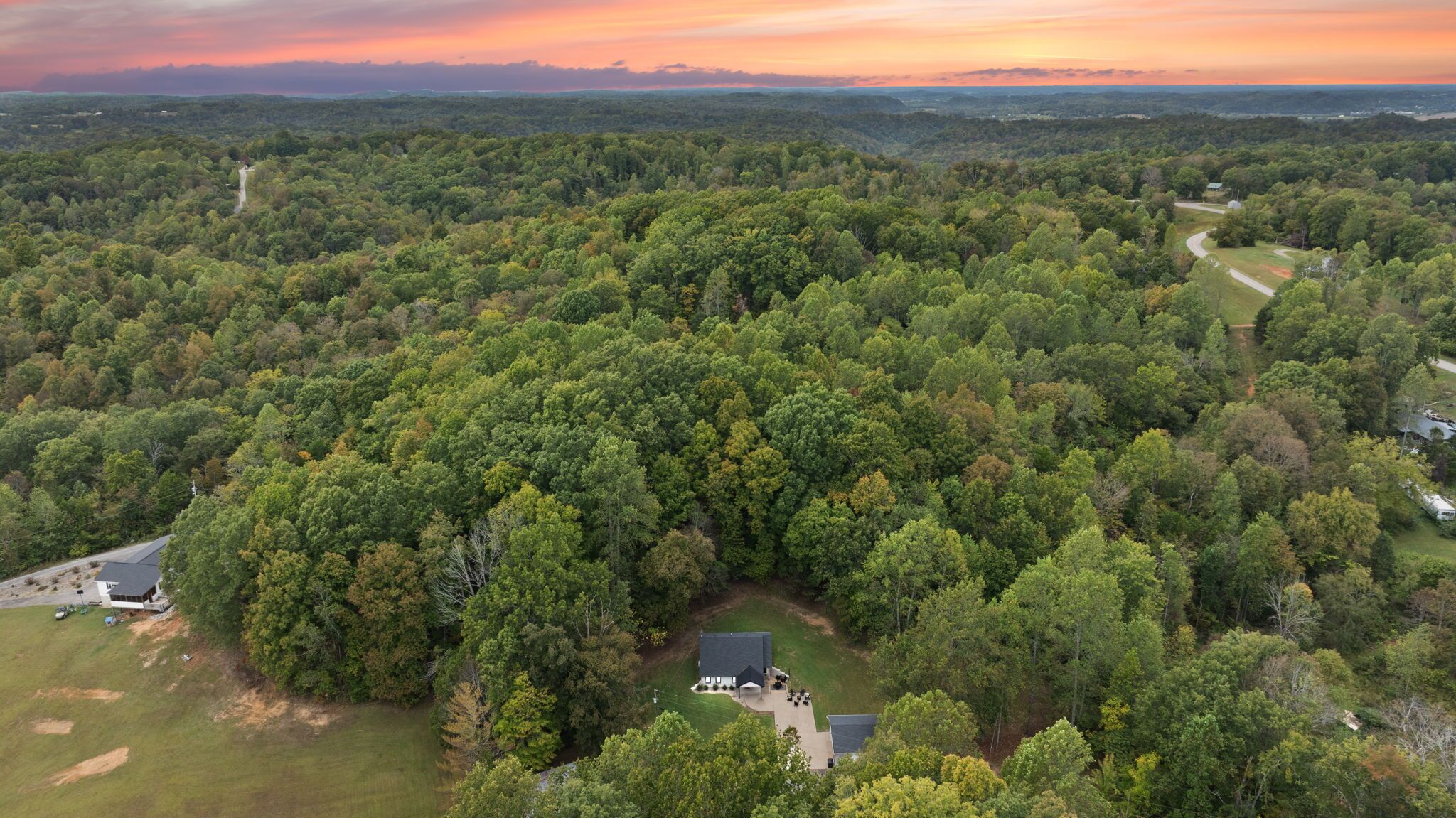 A large forested area with a small house surrounded by trees.