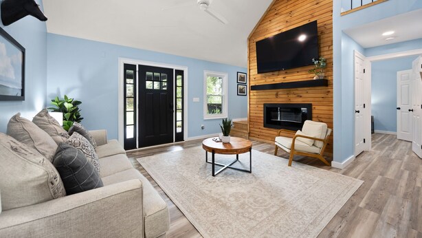 A living room with a beige sofa, a round coffee table, and a wooden accent wall with a TV. - The Cumberland Collective~The Hideaway~<6mi to lake/golf. Great for families! (Burkesville)