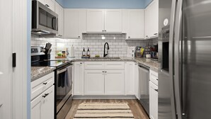 A modern kitchen with white cabinets, a stainless steel refrigerator, a microwave, and a tiled backsplash. - The Cumberland Collective~The Hideaway~<6mi to lake/golf. Great for families! (Burkesville)