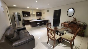 A modern kitchen with a central island, a dining area with a glass table, and a living room with a leather sofa. - WTC Suites (Mexico City)