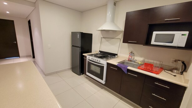 A modern kitchen with a gas stove, oven, microwave, and a refrigerator. - WTC Suites (Mexico City)
