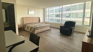 A bedroom with a large bed, a desk, a chair, and a window with a view of buildings. - WTC Suites (Mexico City)