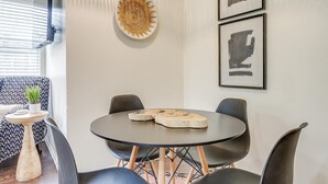 A modern dining area with a round table, black chairs, and a decorative wall piece. - Green Door Cutie Close to Everything in The Fort! (Fort Worth)