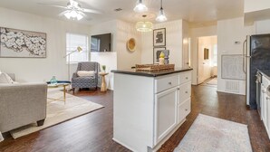 A modern kitchen with white cabinetry, a central island, pendant lights, and a ceiling fan. - Green Door Cutie Close to Everything in The Fort! (Fort Worth)