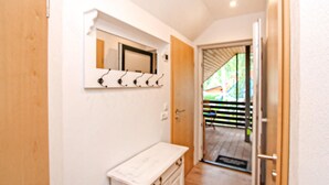 A hallway with a wooden door, a white wall-mounted mirror, and a white cabinet. - Ferienwohnung Bodstedt (Bodstedt)