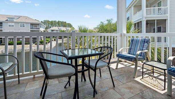 Een terras met een glazen tafel en stoelen, een zwembad en een witte balustrade.