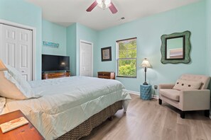 A bedroom with a bed, a TV, a chair, a lamp, and a window with blinds. - 3BR Barefoot Resort Condo in North Myrtle Beach! 🐕 Dog Stays FREE (North Myrtle Beach)