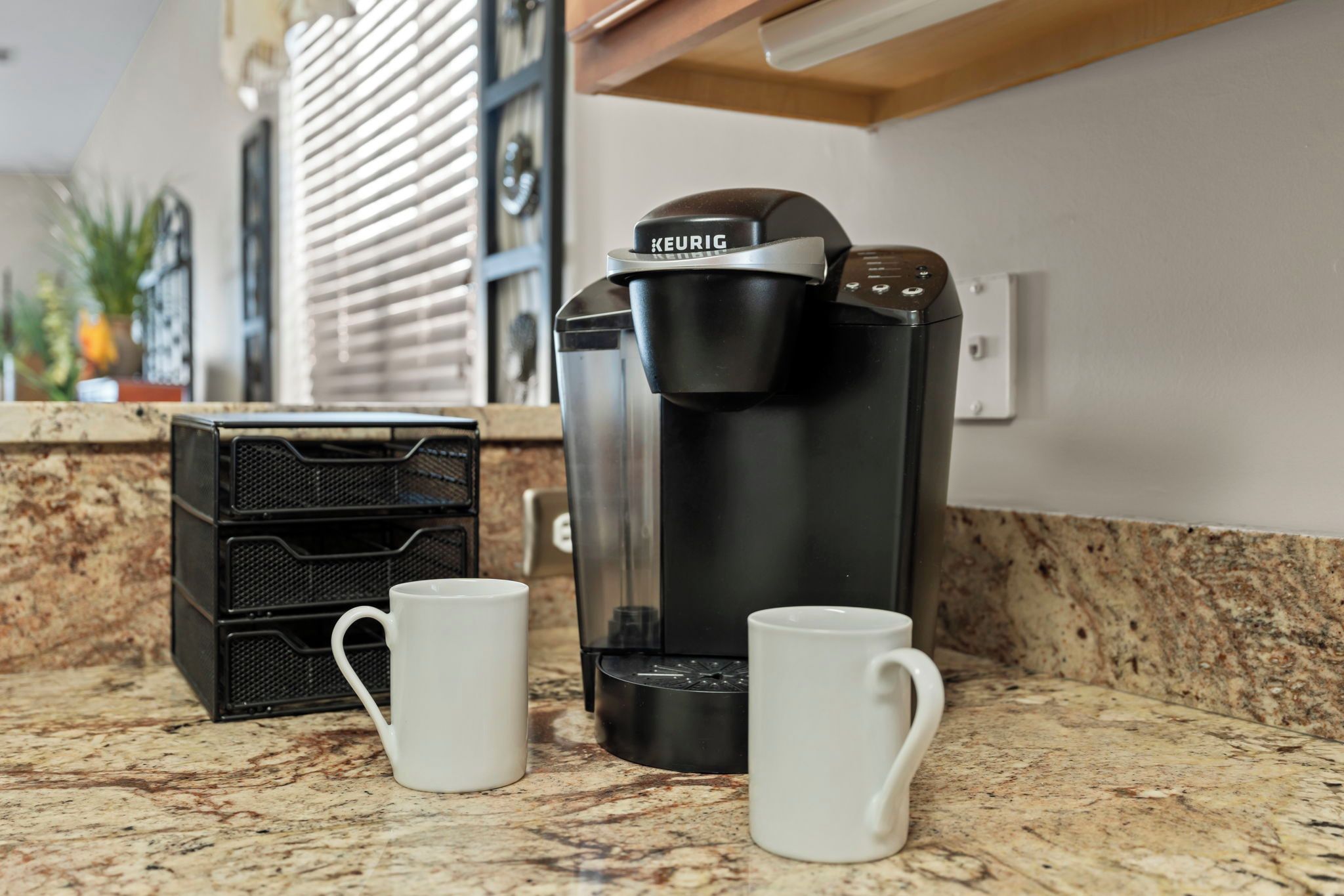 Une machine à café avec deux tasses blanches posées sur un comptoir de cuisine.