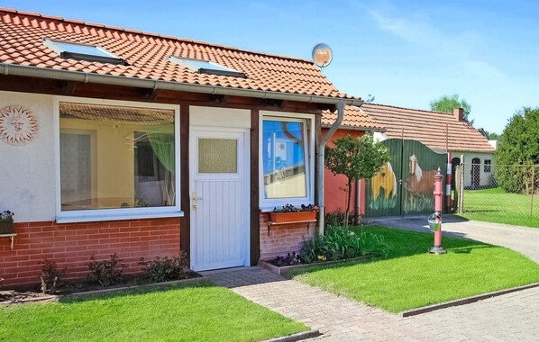 A building with a tiled roof, a white door, and a window with a curtain. - 1 bedroom amazing home in Silz (Silz)