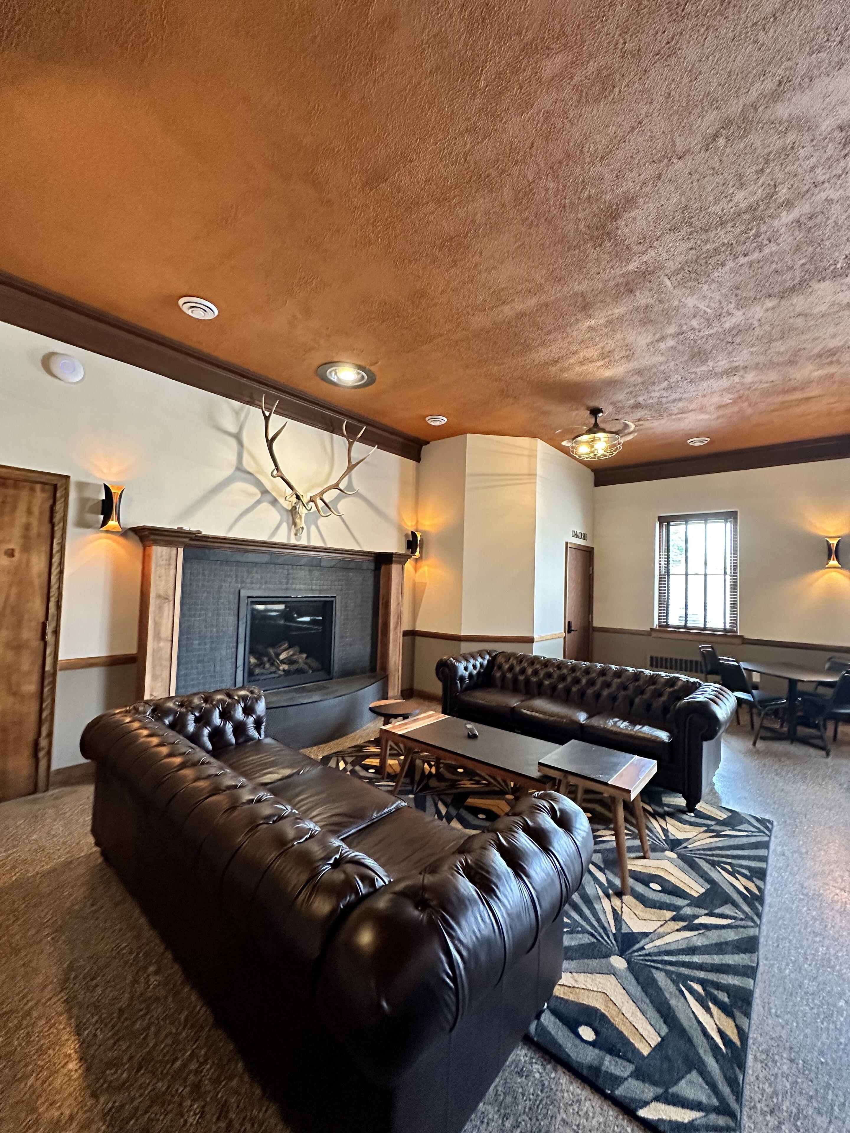 A spacious living room with a fireplace, leather sofas, and a dining area.