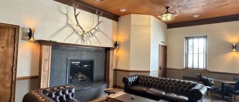 A spacious living room with a fireplace, leather sofas, and a dining area.