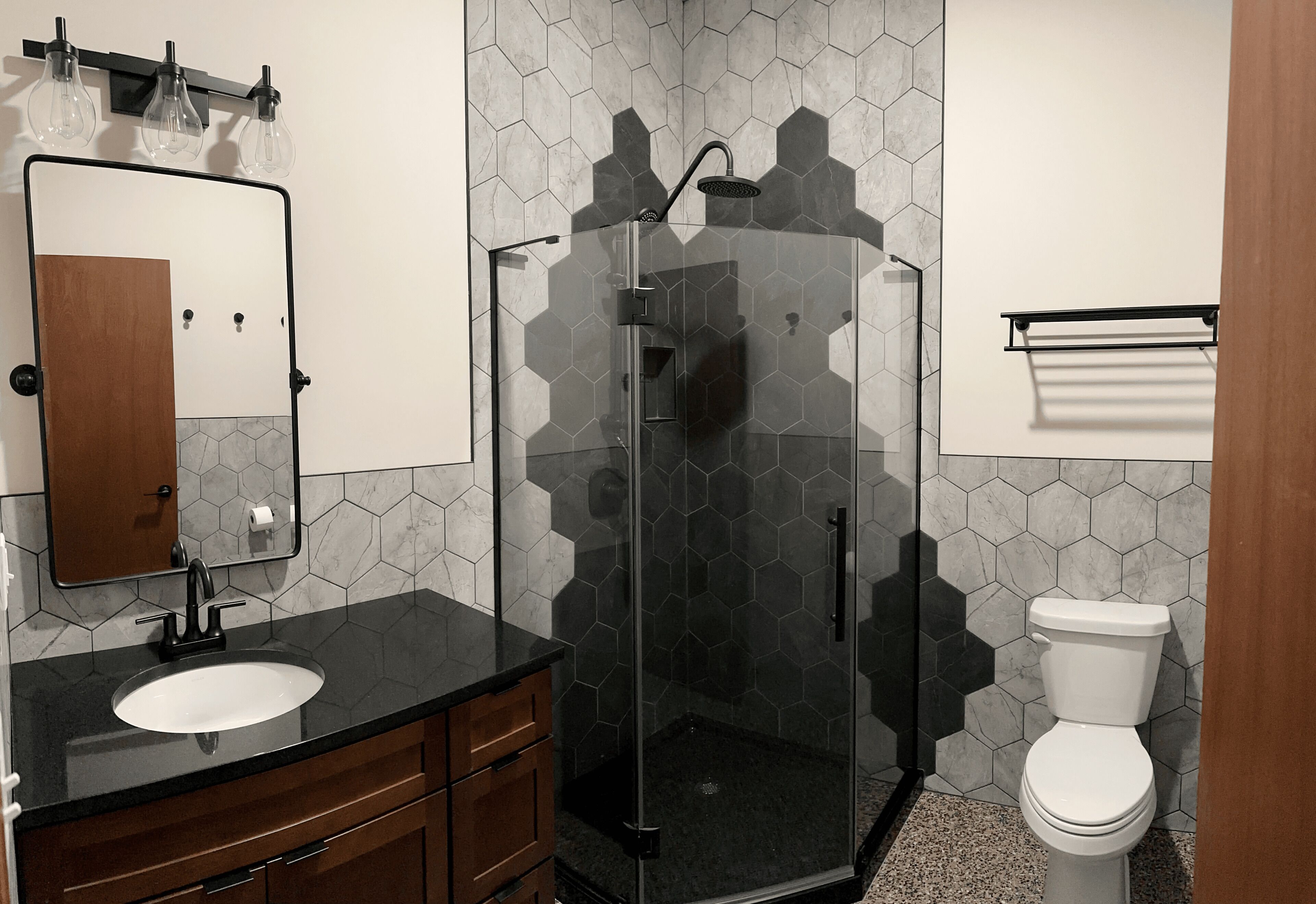 A bathroom with a glass-enclosed shower, a sink with a mirror above it, and a toilet.