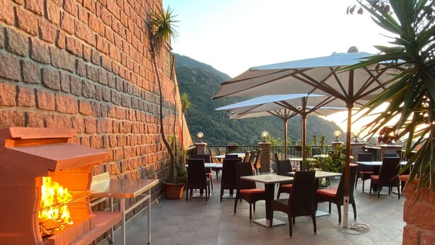 Une terrasse extérieure avec des murs en briques, des tables, des chaises et des parasols.