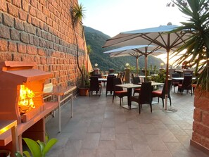 Une terrasse extérieure avec des murs en briques, des tables, des chaises et des parasols.