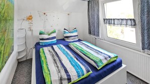 Un lit avec une literie à rayures, une fenêtre avec des rideaux et un mur orné d’un motif texturé.