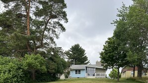 A residential property with a grassy yard, a wooden dock extending into a body of water, and a house in the background. - Cozy 3 bedroom, 1 bath home on Beaver Dam Lake (Beaver Dam)