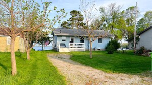 A house with a porch, a gravel path, and a grassy yard. - Cozy 3 bedroom, 1 bath home on Beaver Dam Lake (Beaver Dam)