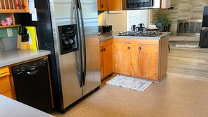 A modern kitchen with stainless steel appliances, wooden cabinets, a built-in microwave, and a kitchen island. - Cozy 3 bedroom, 1 bath home on Beaver Dam Lake (Beaver Dam)