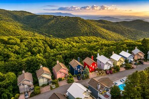 A residential area with houses surrounded by lush greenery and hills in the background.