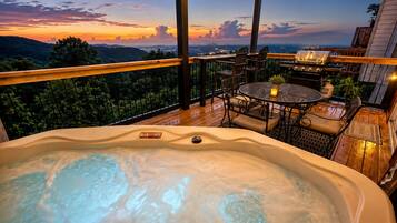Un bain à remous doté d’un panneau de commande, entouré de mobilier d’extérieur et offrant une vue sur le paysage.