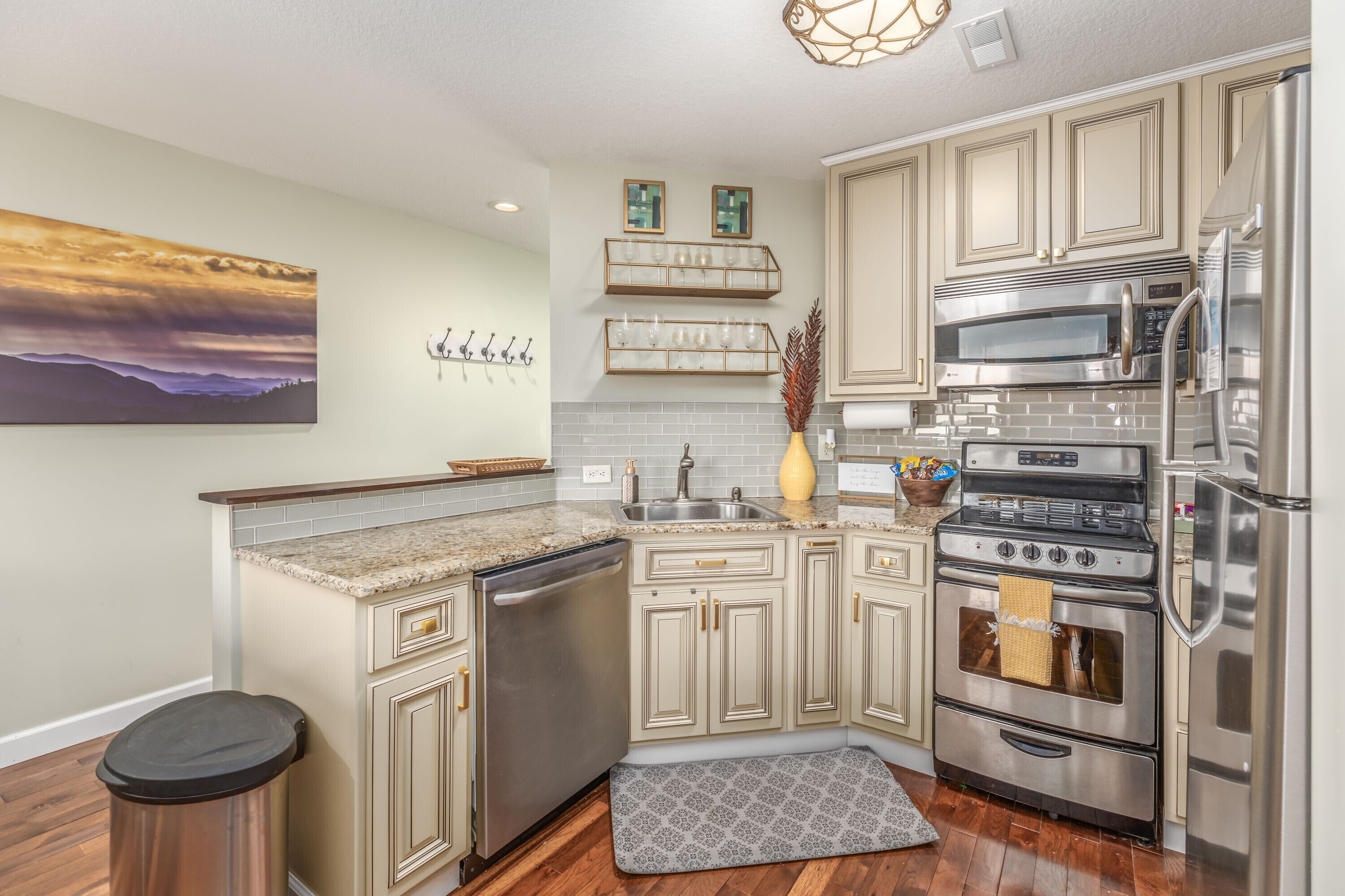 Una cocina con armarios color beige, electrodomésticos de acero inoxidable, encimera de granito y un cuadro decorativo en la pared.