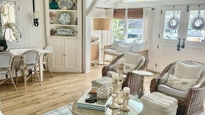 A cozy living room with wicker furniture, a glass coffee table, and a patterned rug. - Balboa Island Beach Cottage (Newport Beach)