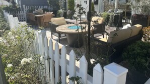 A patio area with outdoor furniture, a pool, and a white picket fence. - Balboa Island Beach Cottage (Newport Beach)