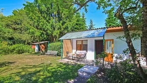Ett litet hus med en uteplats, en bänk och ett bord.