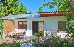 A small house with a covered patio, a table with chairs, and a garden. - Ferienhaus Ueckermünde Seebad (Ueckermünde (Seebad))
