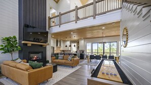 A spacious living area with a fireplace, a sofa, a coffee table, and a foosball table. - Panoramic Mountain Views | Spacious Lodge (Broken Bow)
