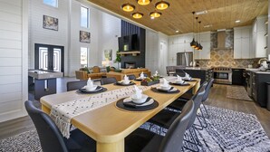 A spacious dining area with a long wooden table set for six, surrounded by modern chairs. - Panoramic Mountain Views | Spacious Lodge (Broken Bow)