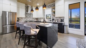 A modern kitchen with a central island, stainless steel appliances, and pendant lighting. - Panoramic Mountain Views | Spacious Lodge (Broken Bow)
