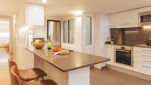 Una cocina moderna con una isla central, armarios blancos, un microondas y un horno.