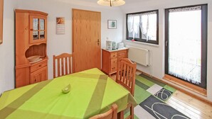 A room with a wooden dining table, chairs, a cabinet, a radiator, and a window with curtains.