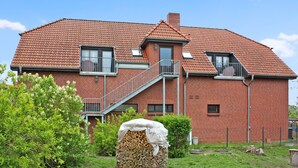 A two-story brick house with a red-tiled roof, a front staircase, and a small balcony.