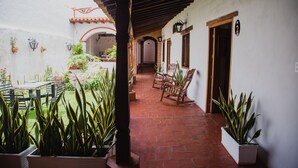 Un patio con un camino de ladrillo, plantas en macetas y mobiliario exterior.