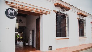 Un edificio blanco con un letrero que indica Hotel Archangelus, que presenta una entrada de ladrillo y ventanas amplias con barrotes.