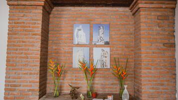 A brick wall with four framed artworks and two vases with orange flowers.