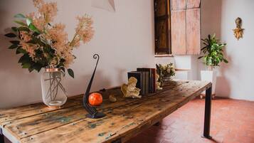 Un tavolo di legno rustico con un vaso di fiori, libri e una piccola statua.
