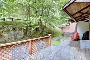 A deck with a metal table and chairs, overlooking a wooded area with a wooden fence and a rocky slope. - Mont Tremblant - Pinoteau Townhouse (Mont-Tremblant)