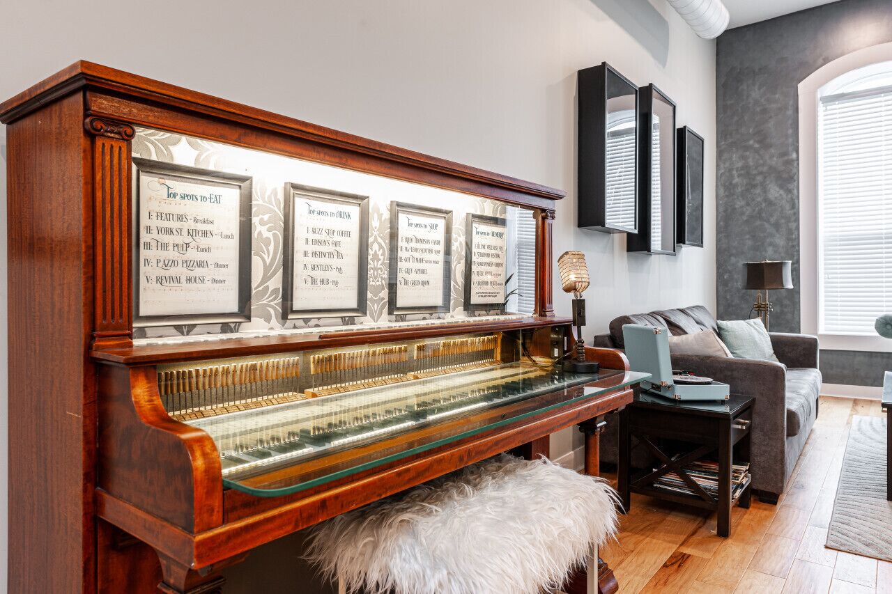 Un piano à queue, des menus encadrés, un canapé confortable et une lampe moderne dans un salon bien éclairé.