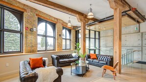 Un espace de détente moderne avec des canapés en cuir, une table basse et de grandes fenêtres.
