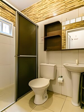 A modern bathroom with a toilet, sink, and a shower area. - Residencial Avó Isaura (Florianópolis)