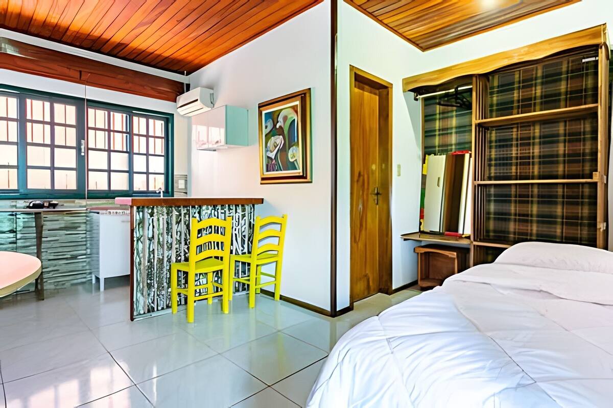 Une chambre moderne avec un grand lit, un bureau avec des chaises et une vue sur la ville grâce à de grandes fenêtres.