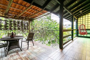 A covered outdoor area with a round table and chairs, a hanging chair, and a view of greenery. - Residencial Avó Isaura (Florianópolis)